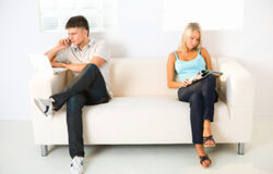 La exención de tributos es aplicable a las disoluciones en que haya efectiva comunidad de bienes Una pareja en un sofá cada uno haciendo algo distinto, separados.