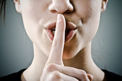 Una chica tapándose la boca en señal de silencio
