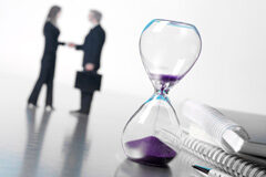 Requisitos y efectos de la contratación a través de las ETT en España Un reloj de arena y al fondo dos personas dándose la mano